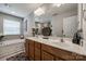 Bright bathroom featuring double sinks, large mirror, and a soaking tub for a spa-like experience at 15613 Troubadour Ln, Huntersville, NC 28078