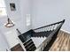 Foyer staircase with black banister, hardwood floors and modern light fixture at 17546 Westmill Ln, Charlotte, NC 28277