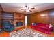 Living room features a brick fireplace, wood paneling, and a red sofa at 2429 Sugar Mill Rd, Charlotte, NC 28210