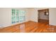 Sunlit living room featuring gleaming hardwood floors and view to dining room at 2429 Sugar Mill Rd, Charlotte, NC 28210