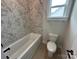 Bathroom features a tub with stylish tile surround, white fixtures, and a window for natural light at 3214 Mcharney Dr # 34, Harrisburg, NC 28075