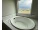 Relaxing soaking tub set against a backdrop of tiled walls and a large window with neighborhood views at 3214 Mcharney Dr # 34, Harrisburg, NC 28075