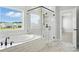 A primary bathroom boasts a glass-enclosed shower, a soaking tub, and a window that overlooks the neighborhood at 3214 Mcharney Dr # 34, Harrisburg, NC 28075