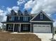 Charming two-story home with a covered porch and a two-car garage, set against a bright blue sky with clouds at 3214 Mcharney Dr # 34, Harrisburg, NC 28075