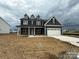 Charming two-story home with a covered porch and a two-car garage on a cloudy day at 3214 Mcharney Dr # 34, Harrisburg, NC 28075