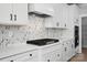 Close-up of a kitchen with a cooktop and custom backsplash, complemented by white countertops at 3214 Mcharney Dr # 34, Harrisburg, NC 28075