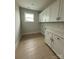 Bright laundry room with white cabinets, light wood flooring, and a window for natural light at 3214 Mcharney Dr # 34, Harrisburg, NC 28075