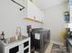 Functional laundry room with a stainless steel sink, modern washer and dryer, and overhead storage at 423 Sensibility Cir, Fort Mill, SC 29708