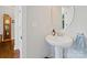 Simple powder room with a pedestal sink, round mirror, and neutral color scheme at 423 Sensibility Cir, Fort Mill, SC 29708