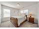A well-lit bedroom featuring a wooden sleigh bed, bedside table, and two windows at 5716 Langwell Ln, Charlotte, NC 28278