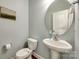 This powder room features a pedestal sink, oval mirror, and hardwood floors at 5716 Langwell Ln, Charlotte, NC 28278