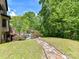Stone path leading to a backyard pool and deck, surrounded by green grass and mature trees at 633 Elmhurst Dr, Fort Mill, SC 29715