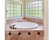 Soaking tub with tile surround and mosaic detail, below frosted window with abundant natural light at 633 Elmhurst Dr, Fort Mill, SC 29715