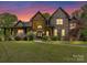 Stunning two-story brick home with a manicured lawn and inviting entrance at dusk at 633 Elmhurst Dr, Fort Mill, SC 29715