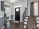 Inviting foyer featuring dark wood floors, stairs with patterned carpet runner, and a black front door with transom window at 653 Gable Oaks Nw Ln, Concord, NC 28027