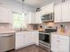 Well-maintained kitchen with white cabinetry, stainless steel appliances, and a window for natural light while cooking at 653 Gable Oaks Nw Ln, Concord, NC 28027