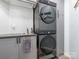 Efficient laundry room with stacked washer/dryer, sleek gray cabinets, and sink for added convenience at 653 Gable Oaks Nw Ln, Concord, NC 28027