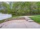 Backyard featuring a concrete patio, brick border, small step ups, a white fence, and mature trees at 6707 Dunton St, Huntersville, NC 28078
