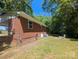 Exterior view of a brick home with a well-maintained backyard, landscaping, and shade trees at 805 Mark Dr, Shelby, NC 28152