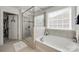 Luxurious bathroom showcasing a soaking tub, separate glass-enclosed shower, and tiled walls at 826 Coralbell Way, Fort Mill, SC 29708