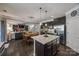 Open kitchen area with an island with barstool seating, granite countertops, stainless steel appliances and dark cabinetry at 826 Coralbell Way, Fort Mill, SC 29708