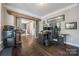 A home office with a barn door entrance, featuring dark wood floors and a view to the dining room at 826 Coralbell Way, Fort Mill, SC 29708