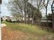 Grassy backyard with a fence and patio set, enhanced by mature trees and a view of neighboring homes at 1110 Valley St, Statesville, NC 28677