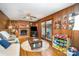 The warm living room has a brick fireplace, wood walls, and a ceiling fan for added comfort at 1620 Edgefield Ave, Gastonia, NC 28052