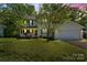 Well-maintained two-story home with a lush front yard, porch, mature trees, and attached garage at 1694 Trotters Ridge Rd, Stanfield, NC 28163