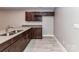 This kitchenette features wooden cabinets, granite countertops, a double sink, and tile floors for easy cleaning at 1805 Axholme Ct, Waxhaw, NC 28173