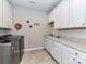 This laundry room includes modern washer and dryer units, tile floors, and plenty of cabinet storage space at 1805 Axholme Ct, Waxhaw, NC 28173