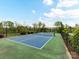 A pristine tennis court with clear markings, netting, and surrounded by fencing and trees on a sunny day at 1805 Axholme Ct, Waxhaw, NC 28173