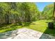 Backyard with a concrete patio, lush green grass, mature trees, and an air conditioning unit at 208 Spinners Dr, Cherryville, NC 28021