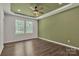 Main bedroom featuring a ceiling fan, wood floors, green accent wall, and natural light from two windows at 208 Spinners Dr, Cherryville, NC 28021