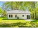 Rear exterior featuring a white home, a concrete patio, lush green grass, and mature trees at 208 Spinners Dr, Cherryville, NC 28021