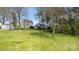 Expansive backyard view showing a two-story home, shed, and additional structure, all nestled among mature trees and lush greenery at 2120 Turtle Point Rd, Charlotte, NC 28262