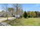 A side view of the two-story home, with a well-maintained lawn and mature trees under a clear sky at 2120 Turtle Point Rd, Charlotte, NC 28262