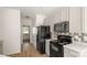 Bright kitchen with white cabinets and black appliances, with hallway and exterior door on view at 2120 Turtle Point Rd, Charlotte, NC 28262