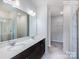 Bright bathroom featuring double sinks, a large mirror, and a walk-in shower with marble tile surround at 2579 Ruby Dixon Crossing Dr # 12, Gastonia, NC 28056