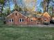 Backyard view of a brick home featuring a stone patio and a lush green lawn at 310 S Poston St, Shelby, NC 28150