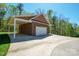 Detached garage with a white garage door, open carport, brick siding, and expansive driveway, providing extra parking at 5016 Woodwinds Ne Dr, Hickory, NC 28601