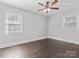Bedroom features a ceiling fan, two windows allowing ample natural light and stylish dark wood floors at 6401 Montpelier Rd, Charlotte, NC 28210