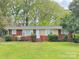 Charming brick home with a well-maintained front yard featuring colorful flowers and lush greenery at 6401 Montpelier Rd, Charlotte, NC 28210