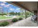 Charming covered porch with wooden floor and white pillars with a pool in the background at 6419 Gilead Rd, Huntersville, NC 28078
