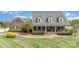 Beautiful brick home with dormer windows, a covered front porch, and a manicured lawn with mature trees at 6419 Gilead Rd, Huntersville, NC 28078