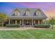Attractive brick home with dormer windows and a columned front porch, set against a vibrant sunset sky at 6419 Gilead Rd, Huntersville, NC 28078