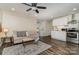 Cozy living room features a couch, ceiling fan and adjoins to a kitchen area with white cabinets and stainless steel appliances at 6419 Gilead Rd, Huntersville, NC 28078