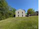 View of the backyard from the side of the home, lush green lawn and trees at 6846 Beverly Springs Dr, Charlotte, NC 28270