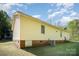 View of home exterior featuring a brick foundation, yellow siding and a well-maintained lawn and air conditioning unit at 700 Fine Wright Ave, York, SC 29745
