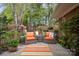 Relaxing patio with orange cushioned seating, potted plants, and beautiful green surroundings at 7444 Hurstbourne Green Dr, Charlotte, NC 28277